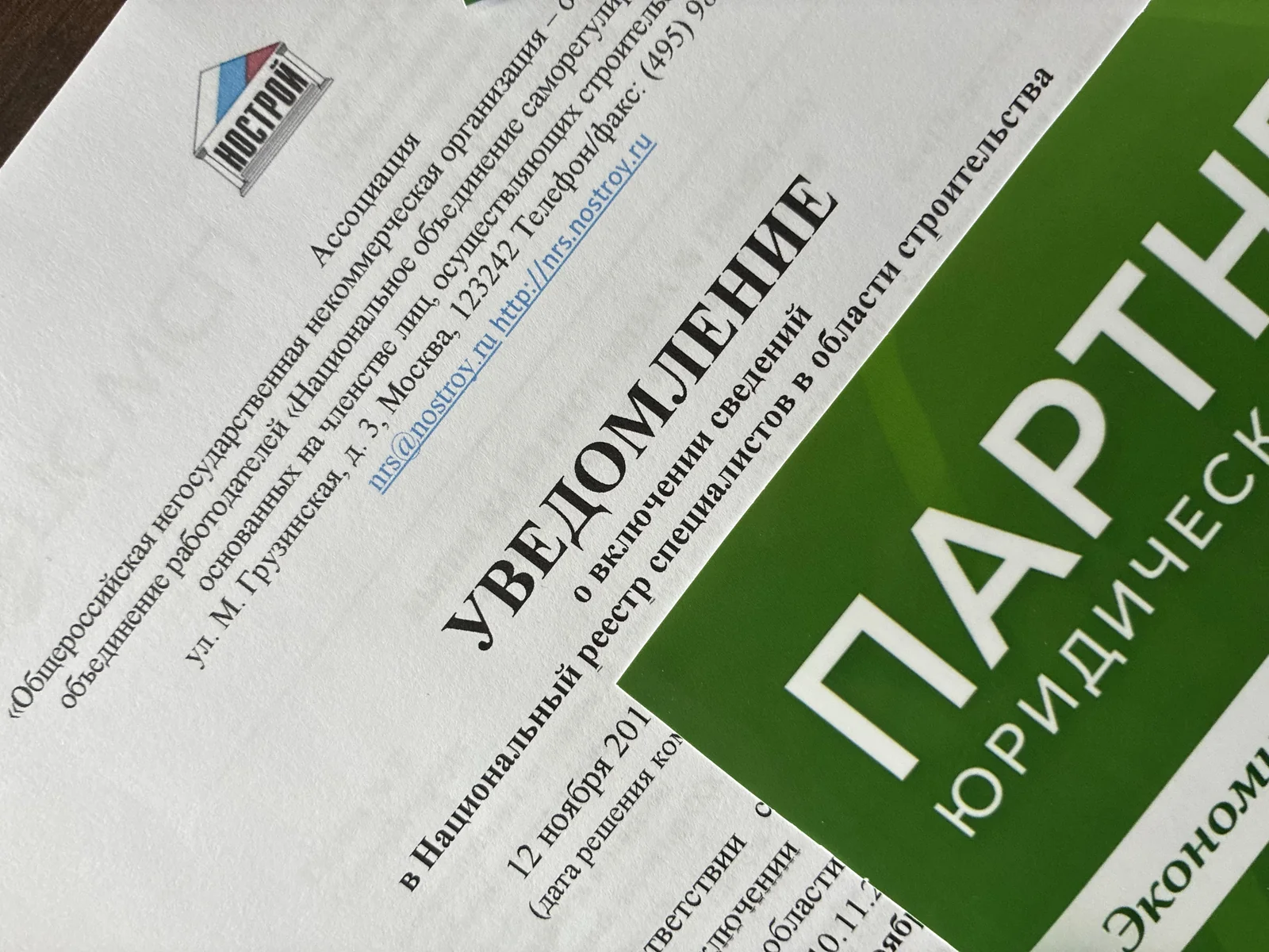 Уведомление НОСТРОЙ о включении сведений в Национальный реестр специалистов рядом с брошюрой Юридической фирмы «Партнёр»